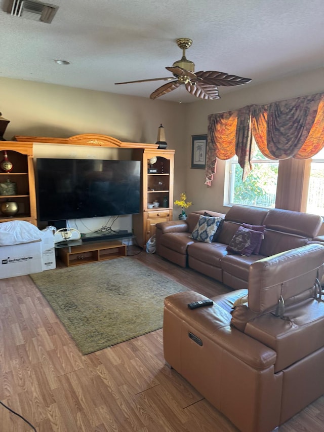 living room featuring a wealth of natural light, light hardwood / wood-style flooring, a textured ceiling, and ceiling fan