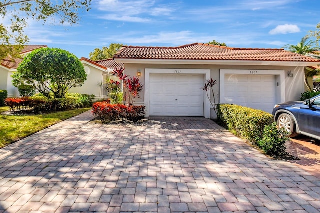 view of front of home with stucco siding, a tiled roof, decorative driveway, and a garage