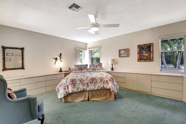 carpeted bedroom featuring ceiling fan and a textured ceiling