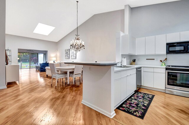 living room featuring hardwood / wood-style floors, a skylight, and high vaulted ceiling