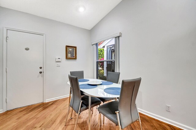 dining room with a notable chandelier, a skylight, high vaulted ceiling, and light hardwood / wood-style floors