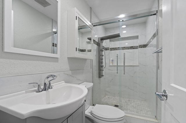 bathroom featuring vanity, toilet, tile walls, and walk in shower