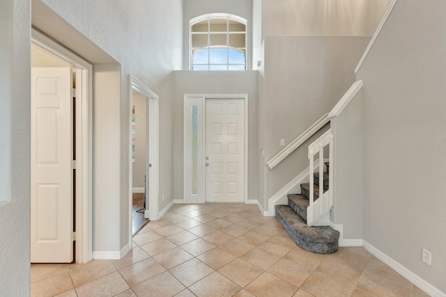 foyer featuring light tile patterned flooring and a towering ceiling