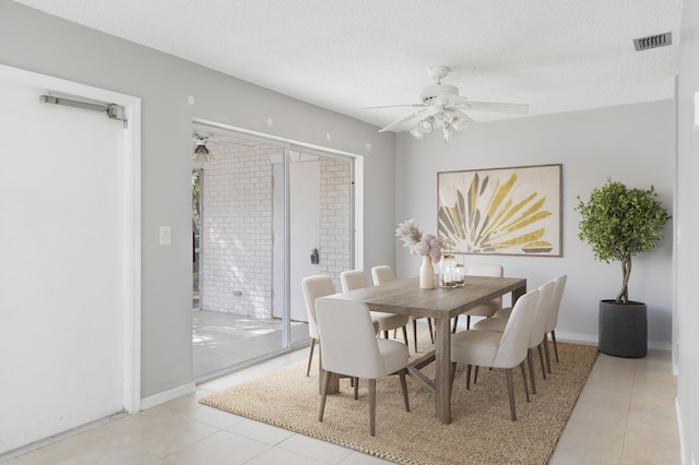 tiled dining space with ceiling fan and a textured ceiling