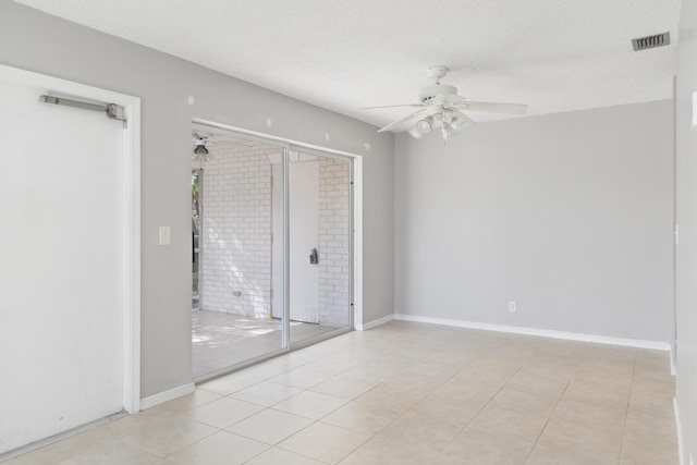 tiled empty room featuring ceiling fan and a textured ceiling