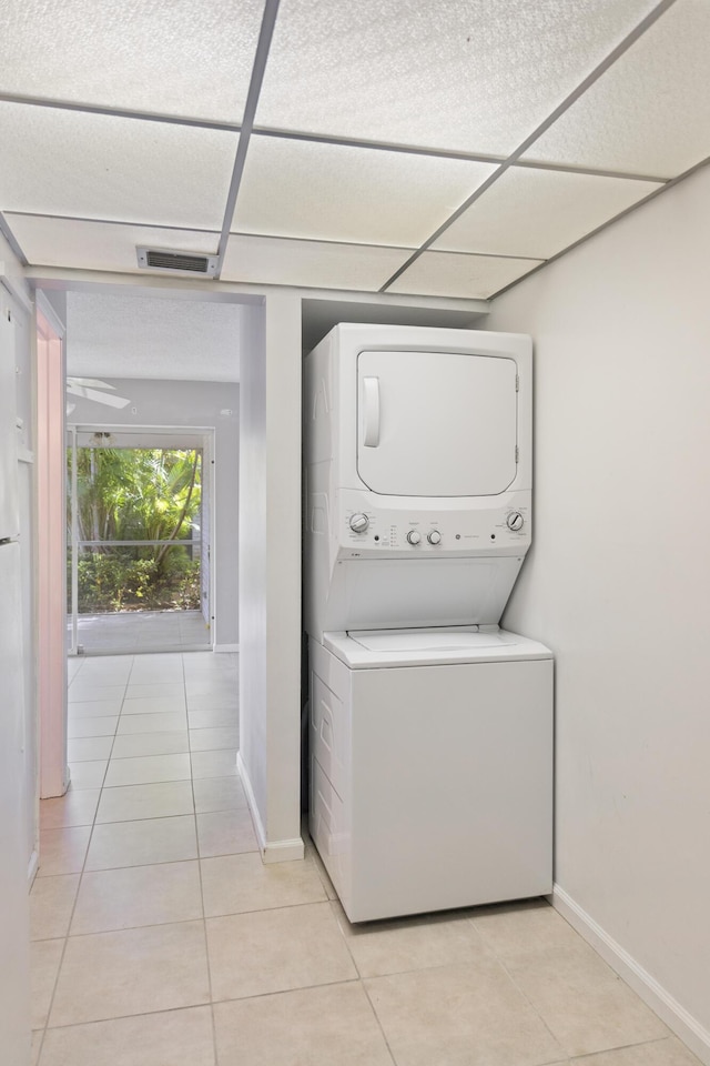 washroom with stacked washer and clothes dryer and light tile patterned floors