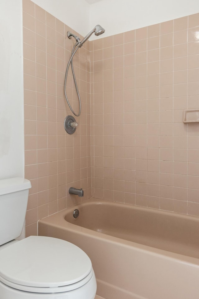 bathroom with toilet and tiled shower / bath