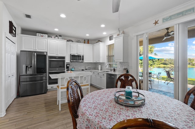 kitchen with a kitchen island, stainless steel appliances, white cabinets, and a water view