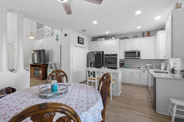 kitchen with ornate columns, white cabinetry, sink, and black appliances