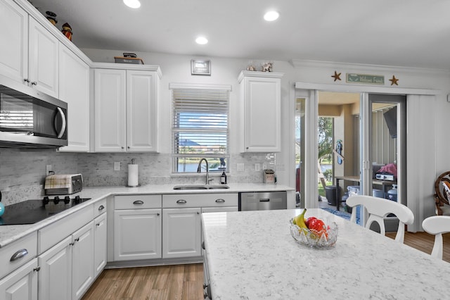 kitchen featuring sink, appliances with stainless steel finishes, tasteful backsplash, light hardwood / wood-style floors, and white cabinets