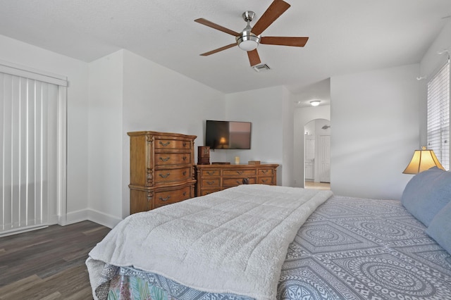 bedroom featuring ceiling fan, connected bathroom, and dark hardwood / wood-style floors