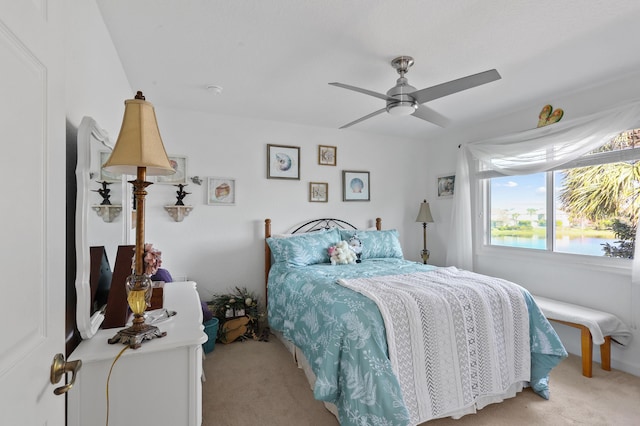 carpeted bedroom featuring a water view and ceiling fan