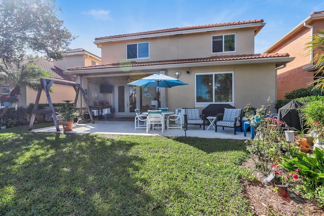 rear view of property with french doors, a patio, and a lawn