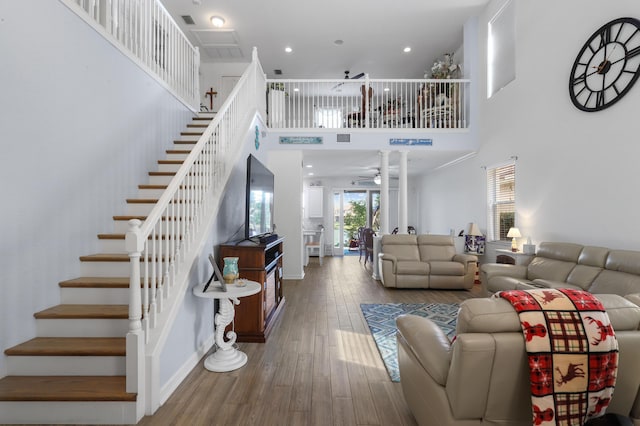 living room featuring a high ceiling, hardwood / wood-style floors, and ceiling fan