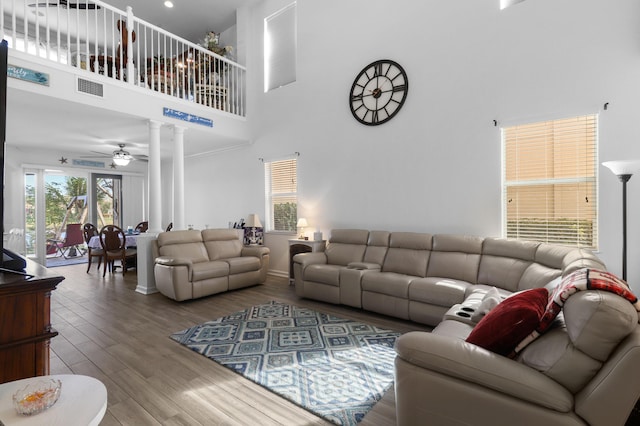 living room featuring ceiling fan, hardwood / wood-style floors, a high ceiling, and ornate columns