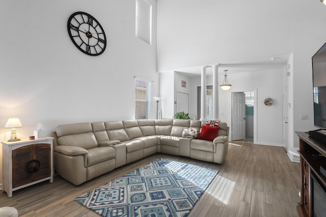 living room featuring hardwood / wood-style floors, a towering ceiling, and decorative columns