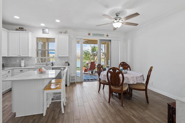 dining area featuring sink, crown molding, wood-type flooring, and ceiling fan