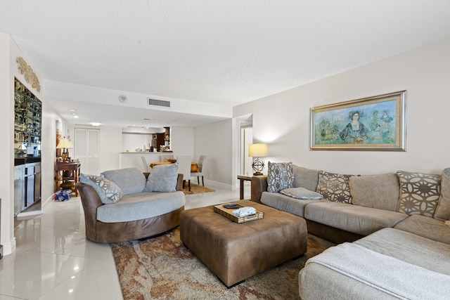 tiled living room with bar and a textured ceiling