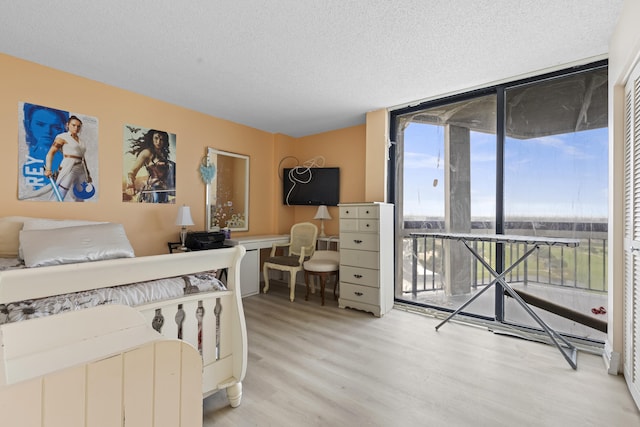 bedroom featuring floor to ceiling windows, hardwood / wood-style floors, a textured ceiling, and access to outside