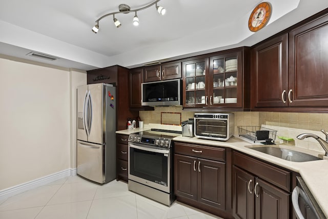 kitchen featuring dark brown cabinetry, stainless steel appliances, sink, and light tile patterned floors