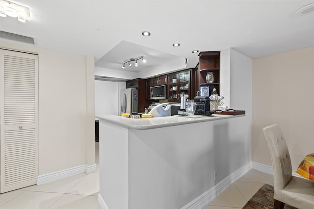 kitchen featuring appliances with stainless steel finishes, dark brown cabinets, light tile patterned floors, and kitchen peninsula