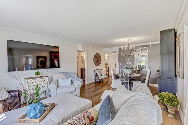 living room featuring hardwood / wood-style floors, a textured ceiling, ornamental molding, and a chandelier