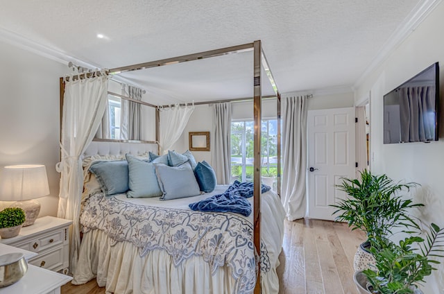 bedroom with crown molding, a textured ceiling, and light hardwood / wood-style flooring