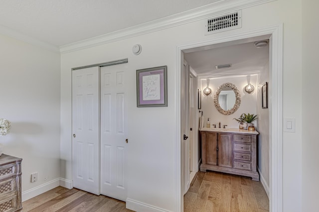 hallway with crown molding, sink, and light hardwood / wood-style flooring