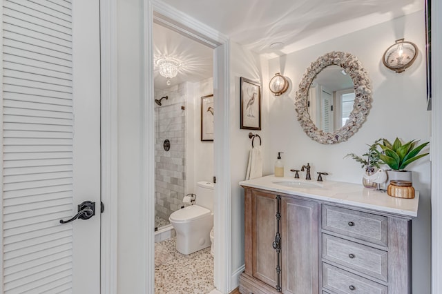 bathroom with vanity, tiled shower, and toilet