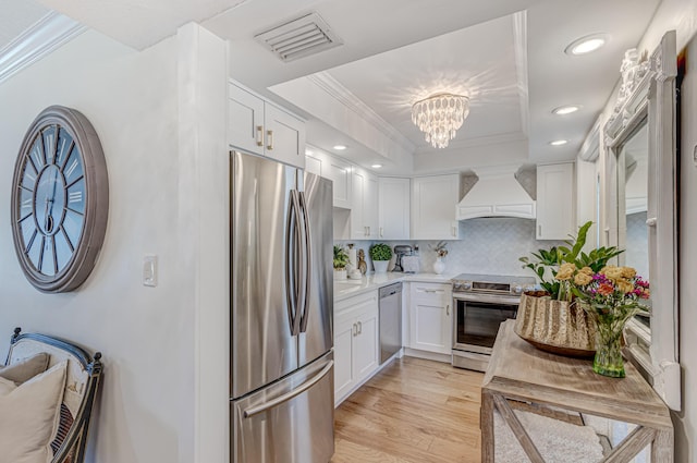 kitchen with appliances with stainless steel finishes, light hardwood / wood-style floors, white cabinets, decorative backsplash, and custom exhaust hood