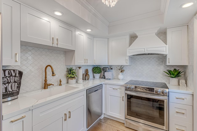 kitchen with backsplash, stainless steel appliances, white cabinets, and premium range hood