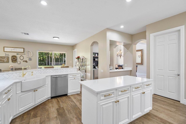 kitchen featuring a textured ceiling, white cabinets, dishwasher, a center island, and light hardwood / wood-style floors