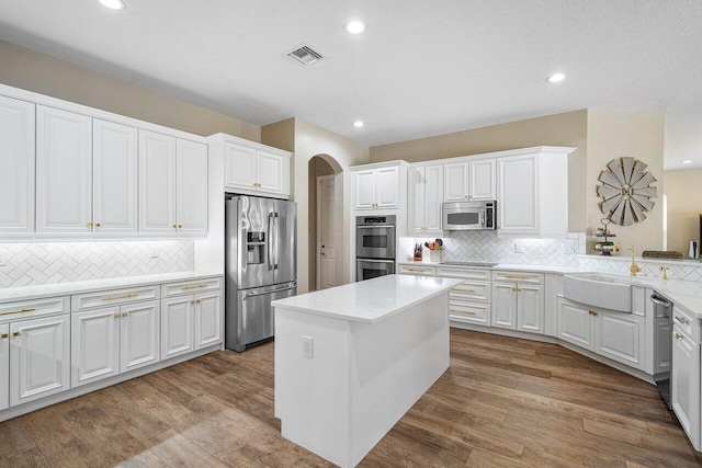 kitchen with stainless steel appliances, tasteful backsplash, a center island, white cabinets, and sink