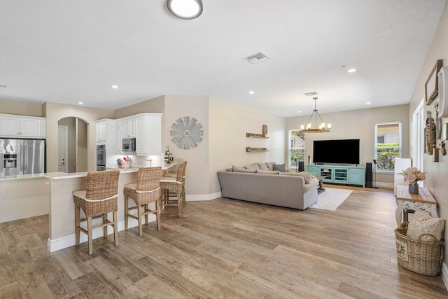 living room featuring light hardwood / wood-style floors, a textured ceiling, and a chandelier