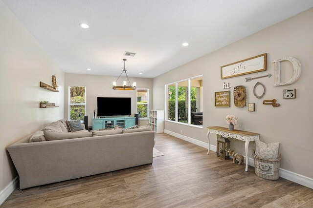 living room featuring a textured ceiling, light hardwood / wood-style flooring, and a notable chandelier