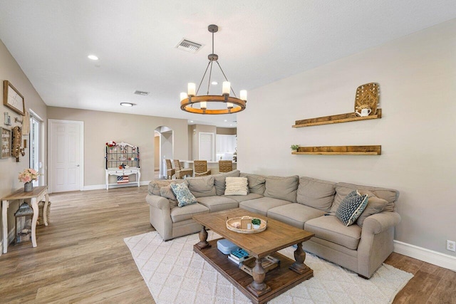 living room featuring light wood-type flooring and a chandelier