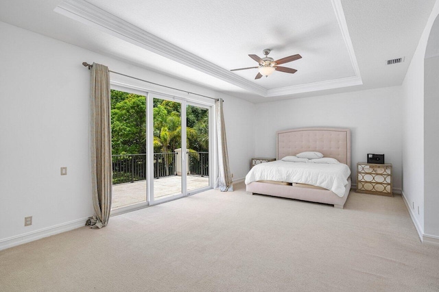 bedroom with carpet floors, access to outside, ceiling fan, a tray ceiling, and crown molding