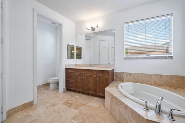 bathroom with toilet, vanity, tiled bath, and a textured ceiling