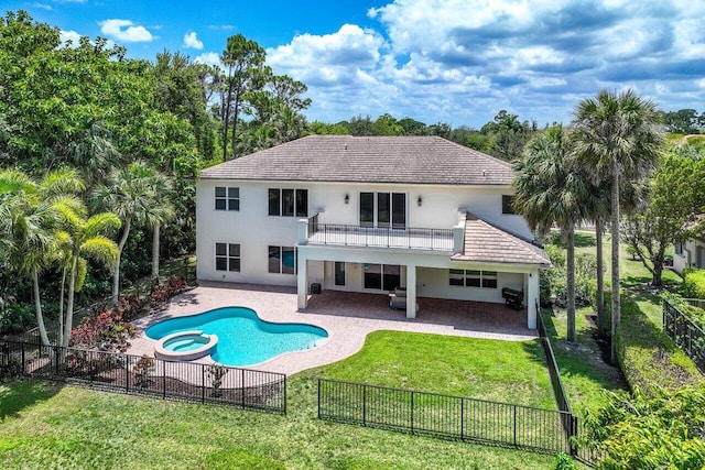 back of property featuring a yard, a swimming pool with hot tub, a balcony, and a patio