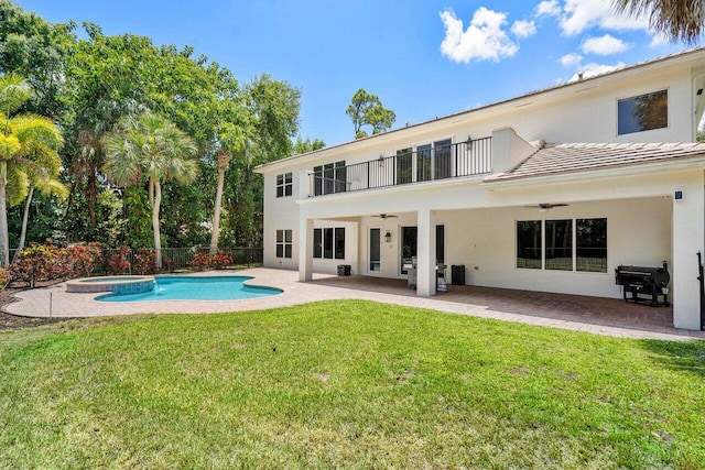 rear view of property with a balcony, ceiling fan, a patio area, and a yard