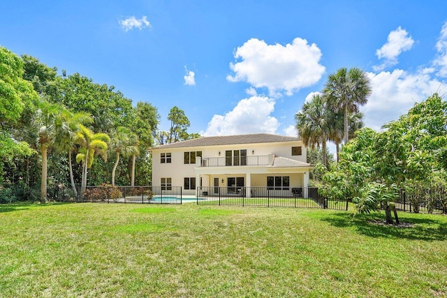 back of house with a lawn, a balcony, and a fenced in pool