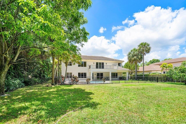 rear view of property featuring a balcony and a yard