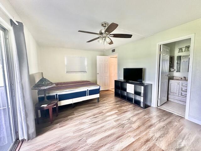 bedroom featuring ceiling fan, ensuite bathroom, and light hardwood / wood-style flooring