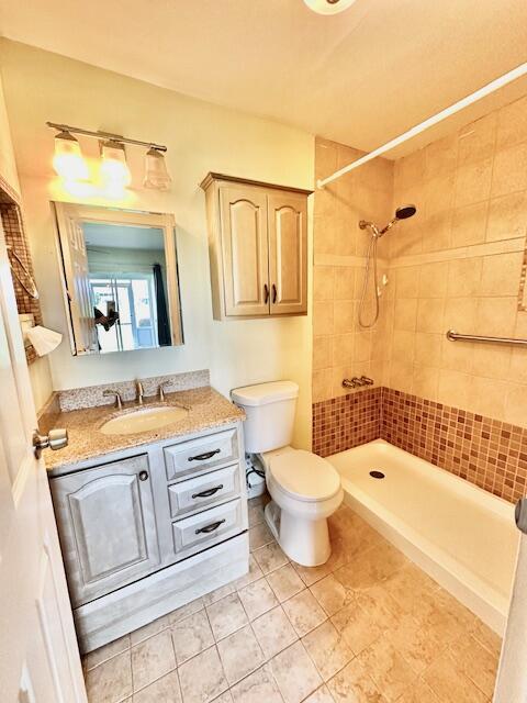 bathroom featuring tiled shower, vanity, toilet, and tile patterned flooring