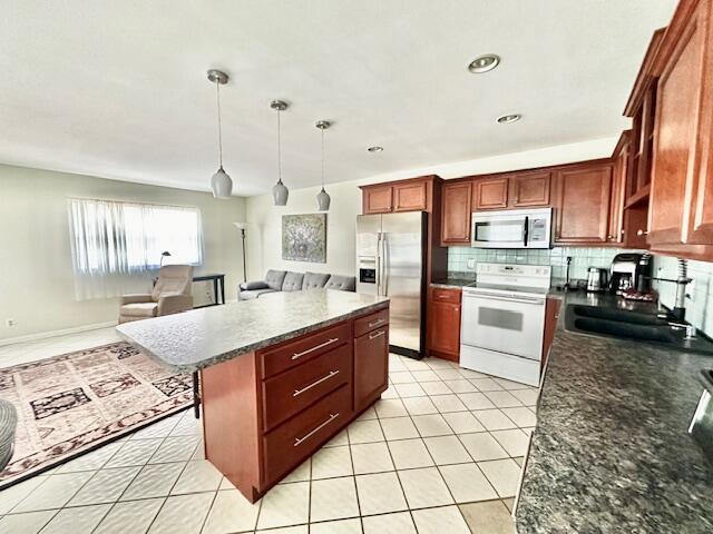 kitchen with a kitchen island, stainless steel appliances, sink, hanging light fixtures, and light tile patterned flooring