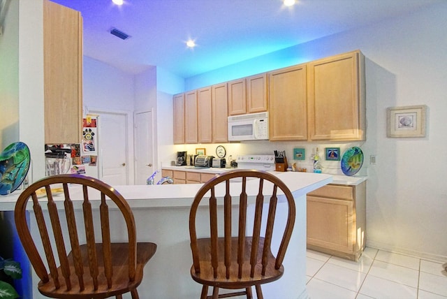 kitchen featuring kitchen peninsula, light tile patterned floors, light brown cabinets, and white appliances