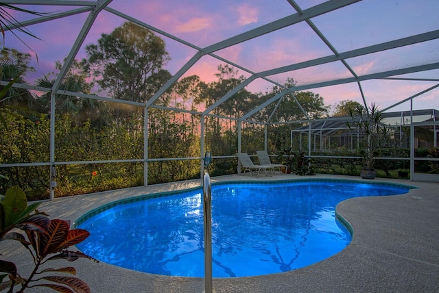 pool at dusk with a patio area and glass enclosure