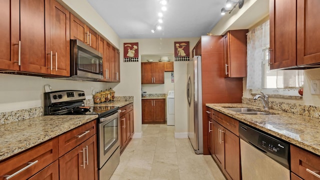 kitchen featuring light stone counters, sink, stainless steel appliances, and washer / clothes dryer