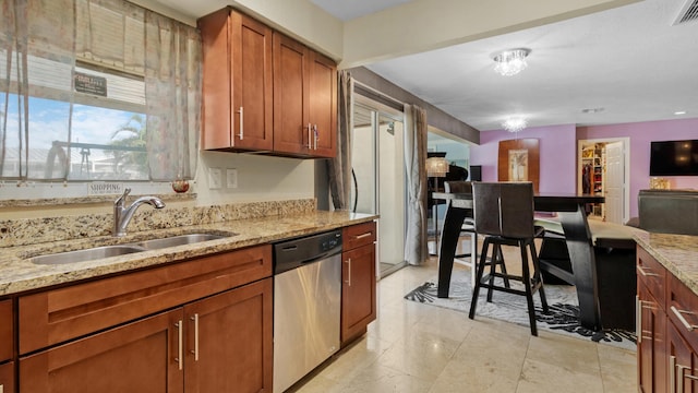 kitchen featuring stainless steel dishwasher, light stone countertops, and sink