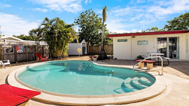 view of pool featuring a shed and a patio